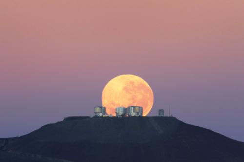 Una splendida Luna piena sorge dietro le cupole del Very Large Telescope.