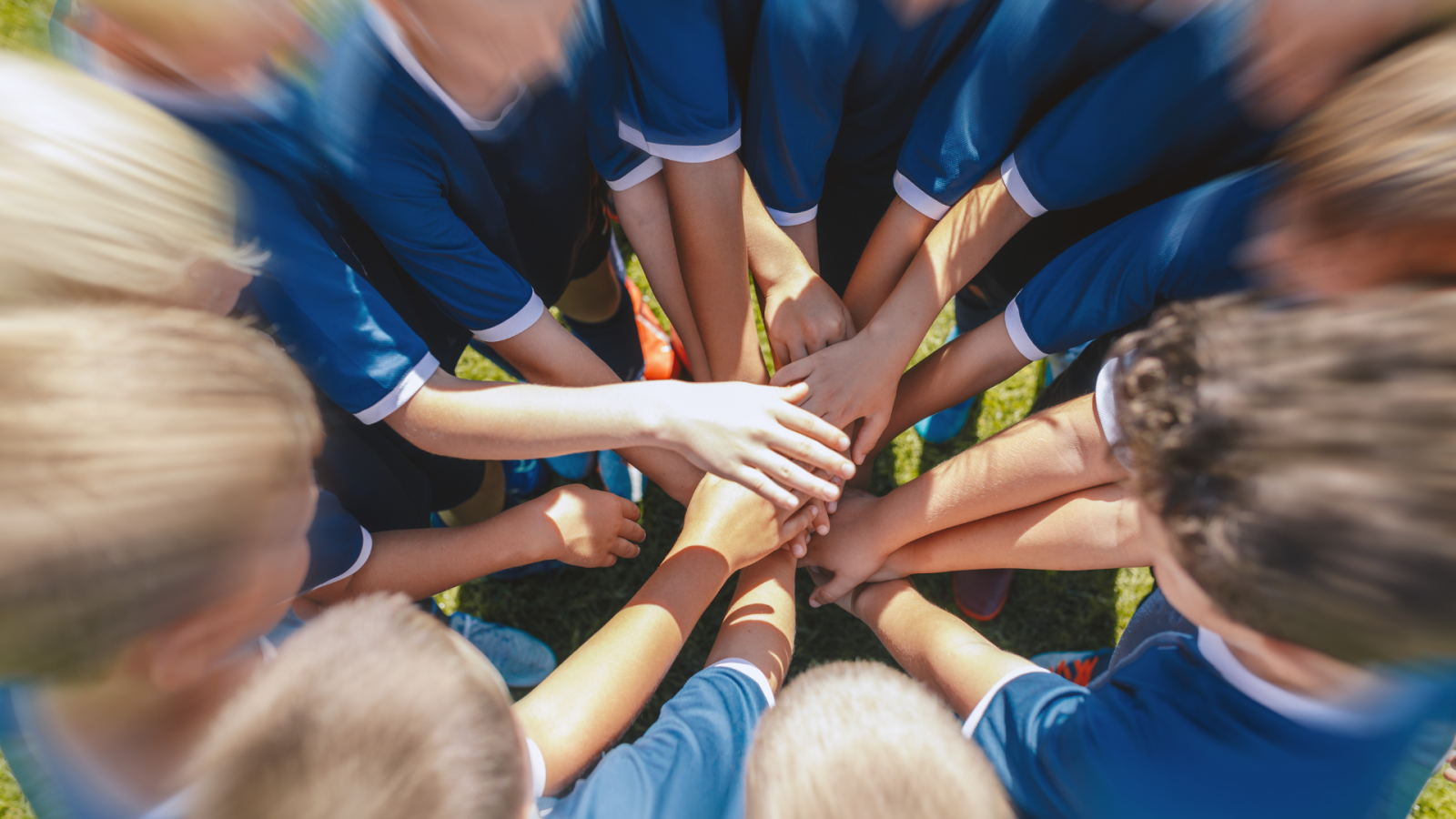 squadra di bambini di cui si vedono le mani unite