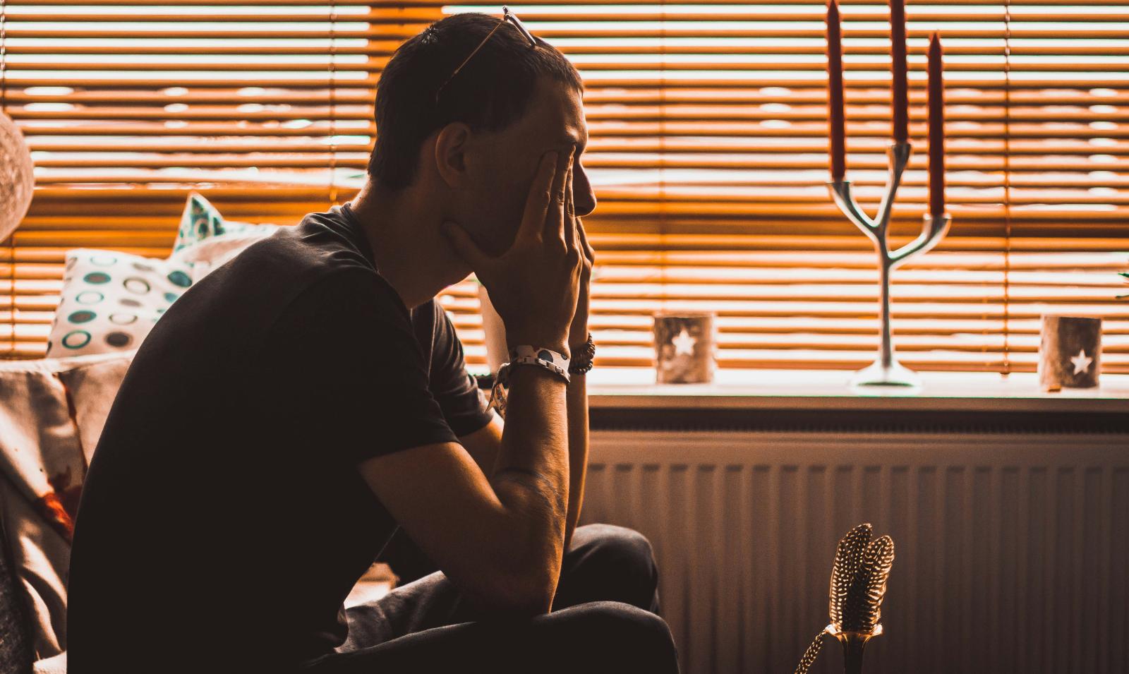 uomo che guarda sconsolato dalla finestra