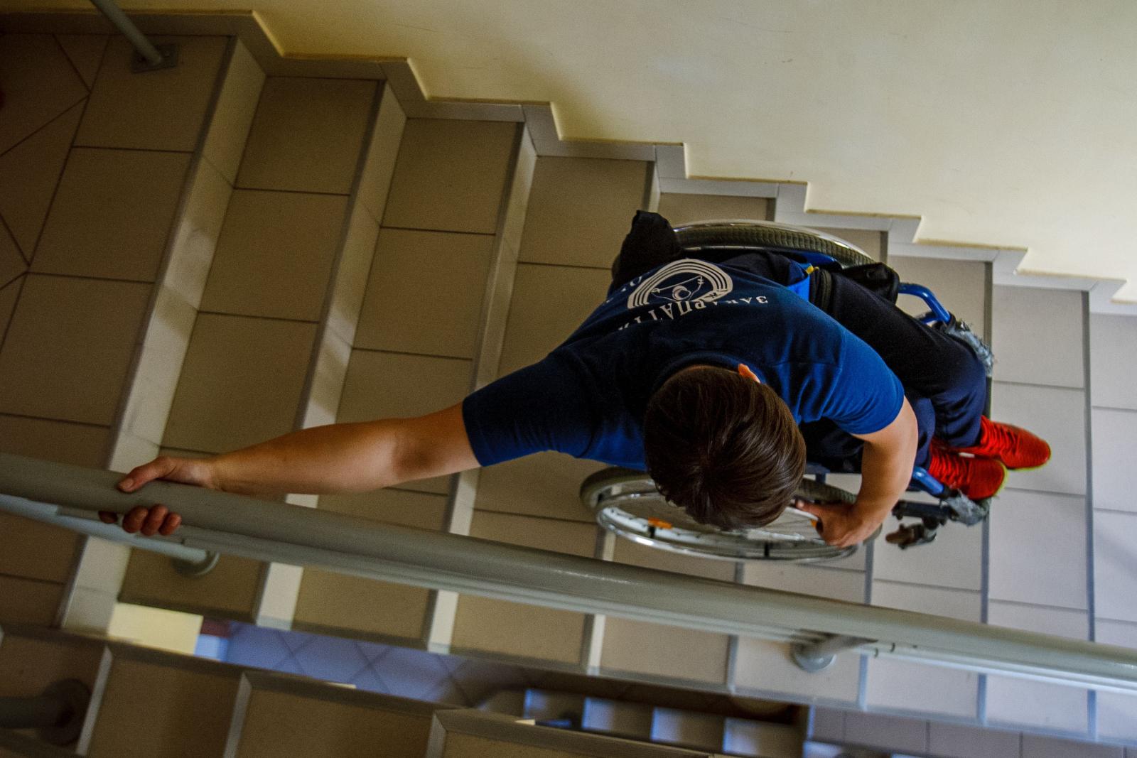 Persona sulle scale in sedia a rotelle