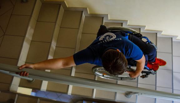 Persona sulle scale in sedia a rotelle