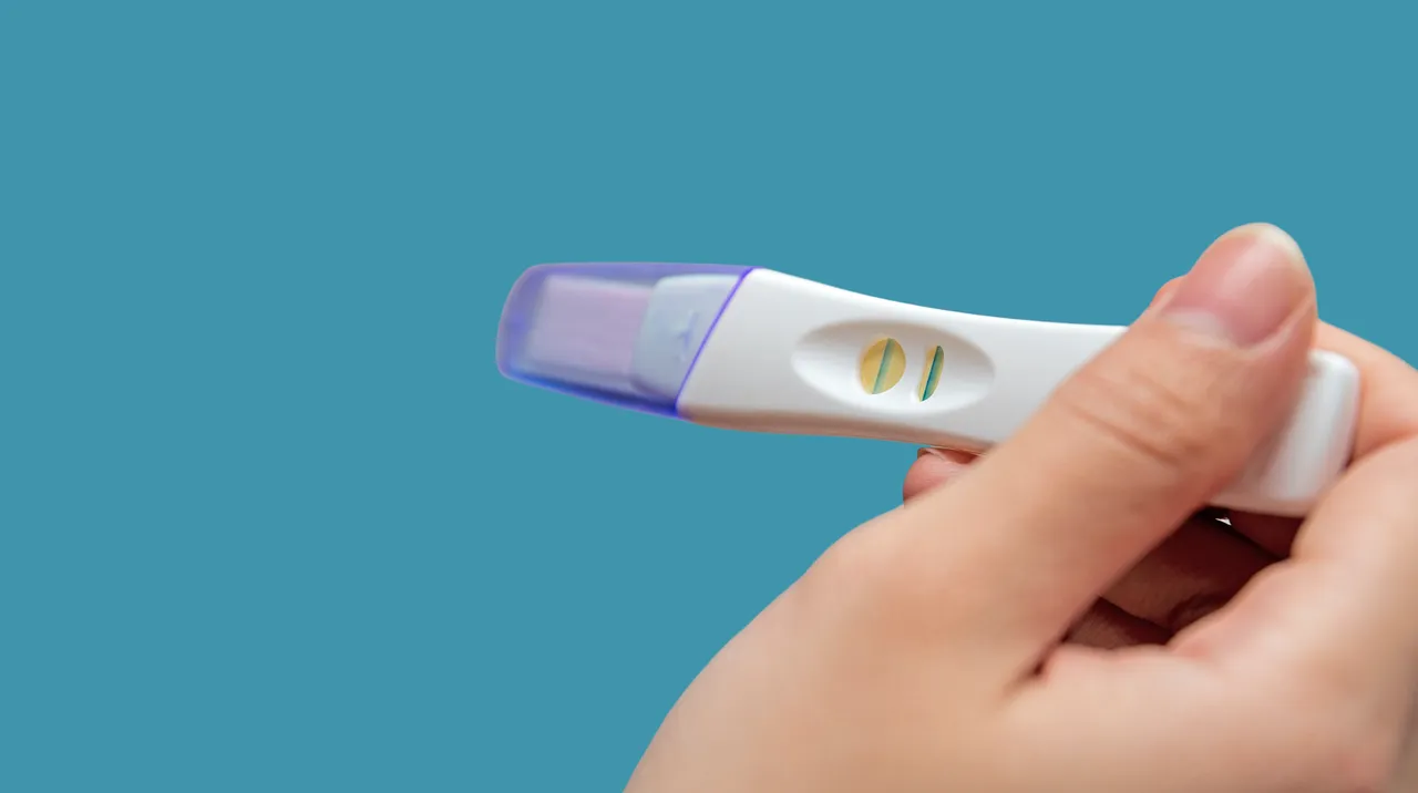 Mano femminile che tiene un test di gravidanza positivo