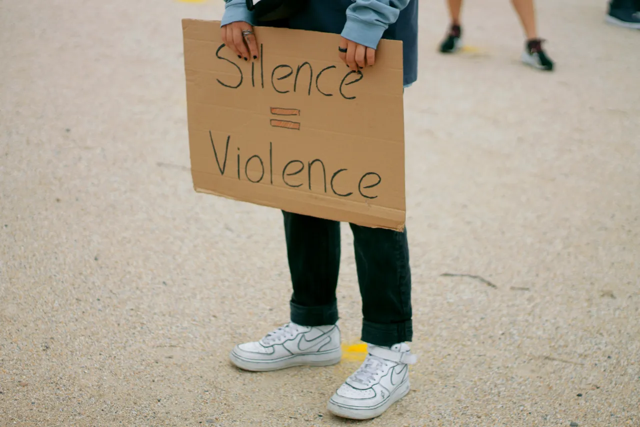 Ragazza che tiene un cartello con su scritto "Silence=Violence"