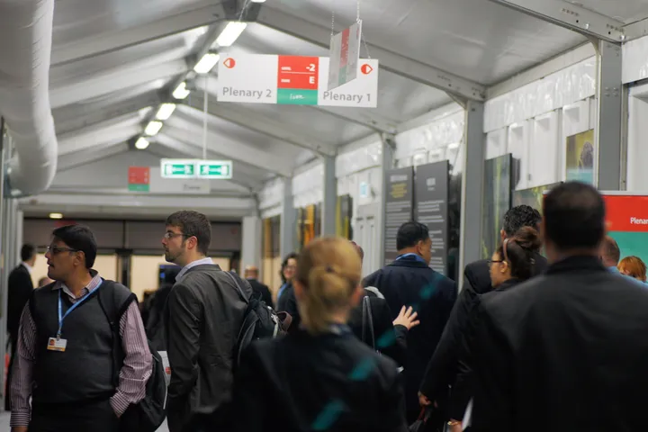 Delegati nei corridoi della COP19 allo Stadio nazionale di Varsavia, sotto i cartelli che indicano le sale plenarie.