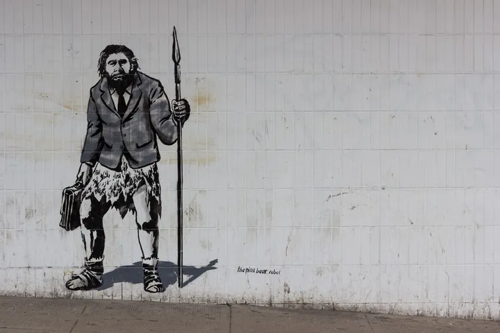 A primitive man with a spear, blazer and briefcase