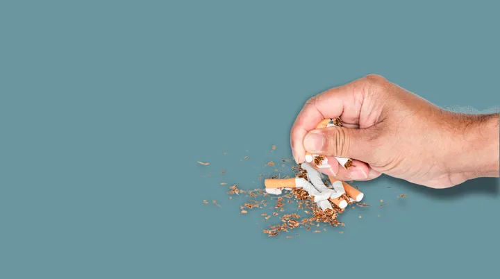 Una mano che distrugge alcune sigarette