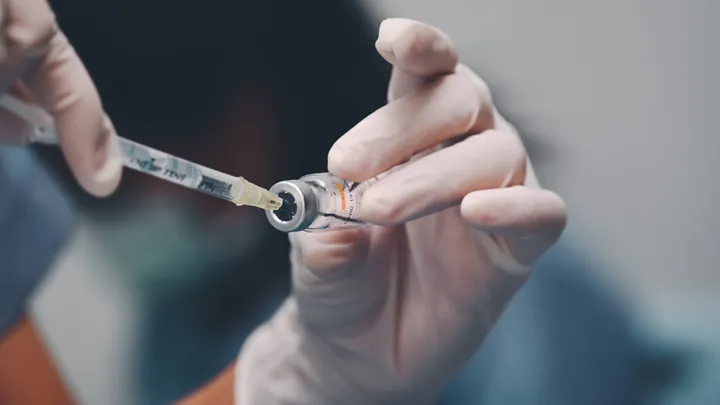 mani che riempiono una siringa da una fiala di vaccino